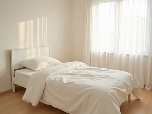 부쿠chon의 고요한 침실에 부드러운 린넨 시트가 놓인 평범한 흰색 싱글 침대가 있는 아늑하고 미니멀한 정물 사진, 자연광이 부드러운 흰색 커튼을 통해 필터링되어 따뜻하고 초대하는 분위기를 자아냅니다.