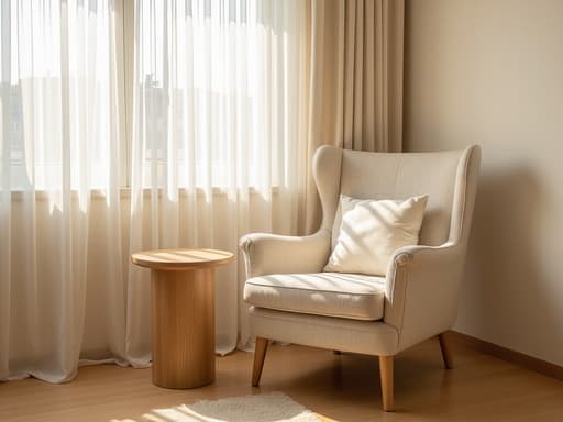 부드러운 패브릭으로 덮인 아늑한 라운지 체어가 부쿡촌의 햇살이 잘 드는 거실에 작은 나무 사이드 테이블과 함께 놓여 있으며, 여기에 부드러운 백색 커튼을 통해 햇빛이 필터링되어 따뜻하고 초대하는 듯한 분위기를 만들어내고 있습니다.