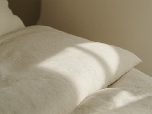 부드럽고 자연스러운 오후 햇살 속에서의 초현실적인 선케어 쿠션, 섬세한 질감, 매끄러운 표면, 미세한 결함, 부드러운 그림자, 반사 품질, 따뜻한 보케 효과로 부드럽게 흐릿한 배경, 따뜻하고 매력적인