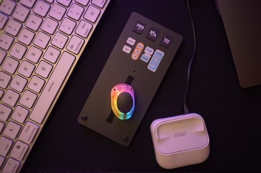 세련된 RGB 백라이트가 있는 컴퓨터 키보드의 고품질 이미지가 현대적인 책상 위에 놓여 있으며, 잘 조명된 홈 오피스의 배경에는 스타일리시한 모니터와 분위기 있는 조명이 있어 전문적이면서도 아늑한 분위기를 자아냅니다.