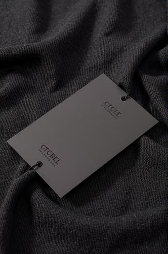 고급스러운 블랙 천이 나무 테이블 위에 우아하게 놓여 있으며, 표면에 부착된 세련된 블랙 라벨이 돋보인다. 부드러운 조명이 천의 질감을 강조하며 세련된 분위기를 자아낸다.