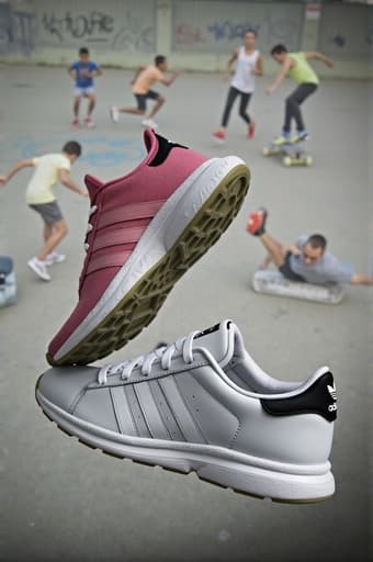 이미지는 최신 Adidas 운동화와 의상을 입은 젊은 인물들이 다양한 활동을 하는 역동적인 도시 장면을 보여줍니다. 그들은 벽에 화려한 그래피티 아트가 있는 주변에서 달리기와 스케이트보드를 타고 있습니다. 브랜드를 강조하기 위해 의상에 아이코닉한 삼선 로고가 뚜렷하게 표시되어 있습니다.