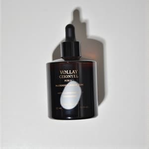 이미지에는 우아한 유리병이 glossy한 검은 액체로 가득 차 있으며, 어두운 조리대 위에 놓여 있습니다. 부드러운 조명이 미세한 반사를 만들어내어 제품의 고급스러움을 강조합니다. 라벨에는 세련된 타이포그래피가 있어 전체적인 신비로움과 우아함을 더하고 있습니다.