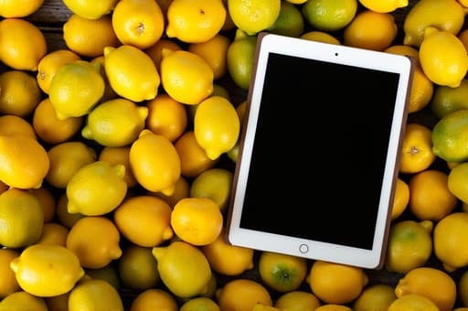 신선한 레몬 더미가 자연광 아래 반짝이며, 거친 나무 테이블 위에 놓여 있습니다. 흐릿한 배경은 아늑한 주방 분위기를 암시하며, 장면에 신선함과 활력을 더해줍니다.