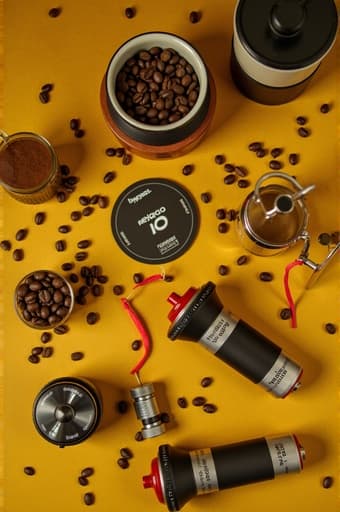 고급 커피 원두, 세련된 그라인더, 에스프레소 머신, 클래식 프렌치 프레스를 갖춘 아름답게 정돈된 커피 제조 세트업이 나무 주방 조리대 위에 놓여 있습니다. 따뜻한 조명과 아늑한 주방 배경이 커피 애호가들에게 완벽한 초대하는 분위기를 만들어냅니다.