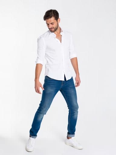 세련된 캐주얼 의상(흰색 셔츠와 청바지)을 입은 30대 중반의 유럽계 남성이 현대적인 스튜디오에서 지루한 표정을 지으며 춤추고 있습니다. 밝은 조명과 깔끔한 배경이 그의 움직임을 강조하여 친근하고 매력적인 장면을 만들어냅니다.