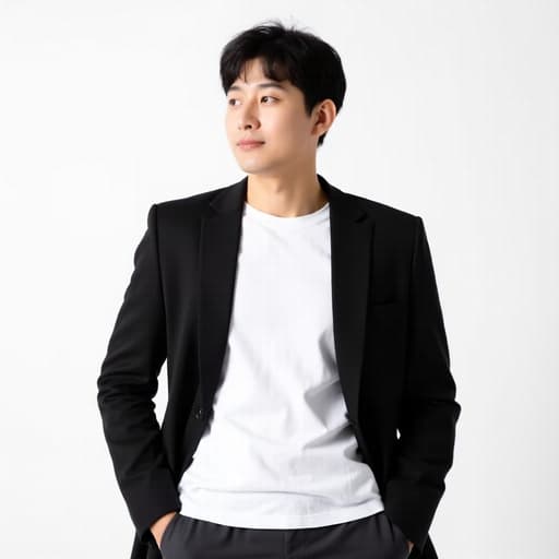 이 이미지는 20대 후반의 자신감 넘치는 한국 남성이 현대적인 블랙 재킷, 화이트 티셔츠, 세련된 슬랙스를 착용하고 있는 반신 촬영을 보여줍니다. 그는 손을 주머니에 넣고 편안하게 서 있으며, 깔끔한 화이트 스튜디오 배경에서 우아함과 자신감을 발산하고 있습니다.