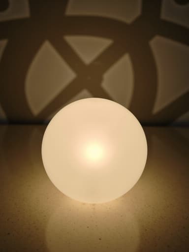 질감 있는 표면 위에 중앙에 있는 무드등, 기하학적 패턴 배경, 부드러운 자연광이 부드러운 그림자를 드리우며, 램프 표면의 미세한 결점.