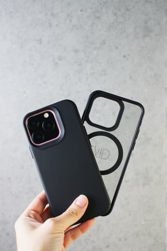 한 사람이 세련된 블랙 아이폰 케이스를 손에 들고 있으며, 그 디자인이 드러납니다. 배경에는 흐릿한 현대 도시 풍경이 자리잡고 있어 세련된 도시 라이프스타일을 강조합니다. 부드러운 자연광이 케이스의 디테일과 질감을 강조하여 매력적이고 바람직한 느낌을 줍니다.